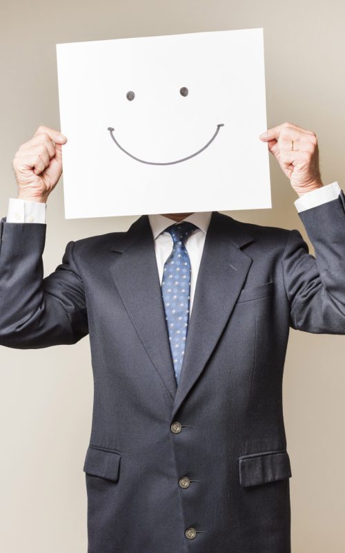 businessman-with-smile-paper-covering-his-face businessman-with-smile-paper-covering-his-face